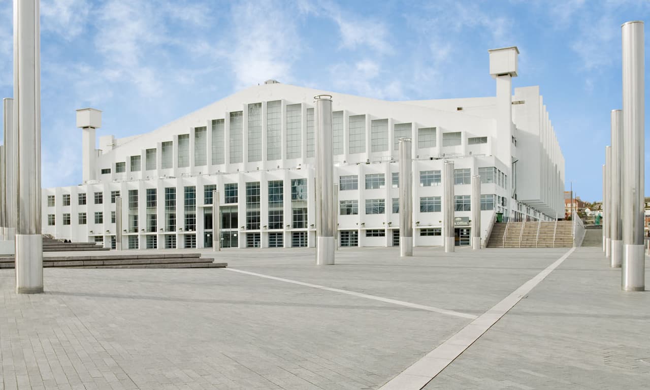 The white art deco frontage of Wembley Arena in London, seen across the empty square in front of it.