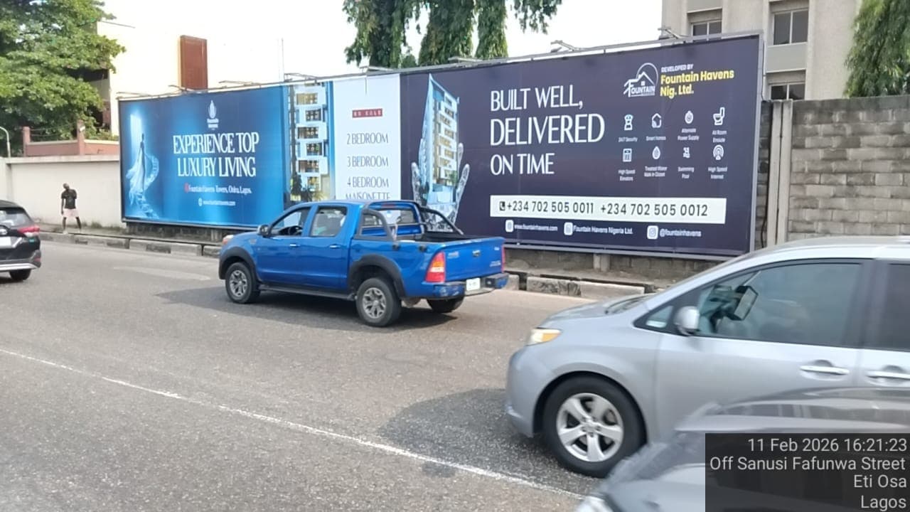 Wider view of the Fountain Havens billboard off Sanusi Fafunwa Street, with traffic passing.