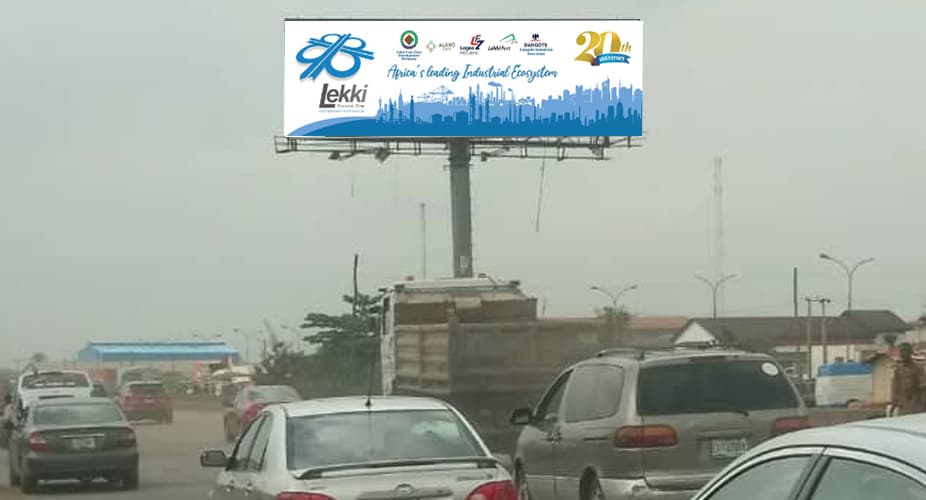 Lekki Free Zone billboard seen through haze above expressway traffic.