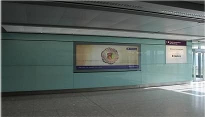 First Bank lightbox on the glazed wall of a Heathrow terminal, beside the B Gates sign.