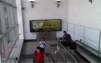Travellers on the escalator beneath the Nigeria — Good People, Great Nation panel at Heathrow.
